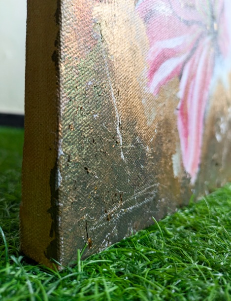 Gold and pink edge of a canvas on grass